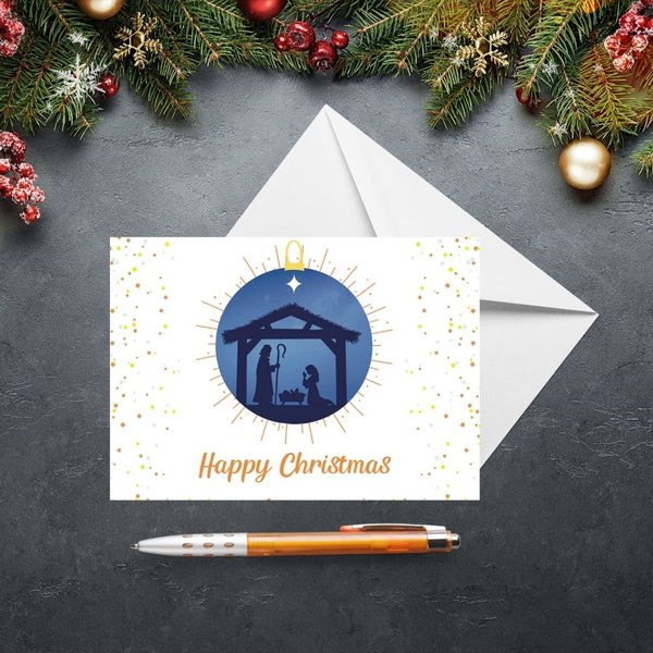 This Mary, Martha & Meg Christmas Card features a Nativity scene showing the silhouettes of Mary and Joseph in a stable, worshipping baby Jesus lying in a manger. The scene is captured inside a Christmas bauble of an inky blue sky, with golden lines outside the bauble. Golden stars frame the sides of the card. The text on the card reads ‘Happy Christmas.’ The card is photographed on a slate gray background with Christmas fir tree branches and festive decorations.