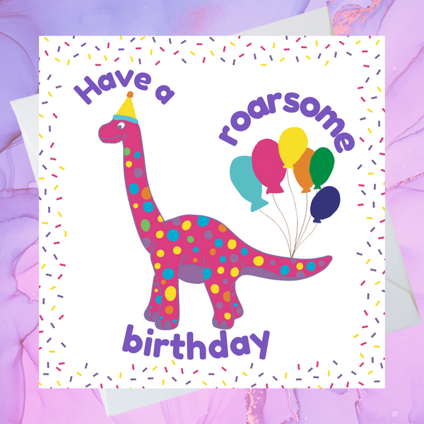 A Mary Martha & Meg child’s birthday card featuring a friendly, pink, dotty, dinosaur with party balloons tied to its tail. The text reads, ‘Have a roarsome birthday.’ The crisp white card has a colourful confetti border. A white envelope peeps out behind the card. The card is placed on a pale lilac background.