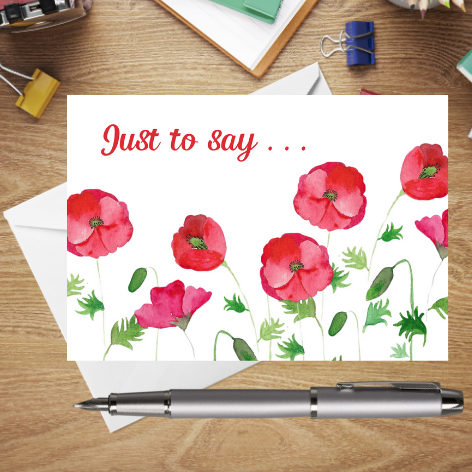 A beautiful postcard created from an original Mary, Martha & Meg hand-painted watercolour. This beautiful design features red poppies with the text in the top right corner reading, ‘Just to say …’ It is a perfect postcard for keeping at hand when you just want to write a note to someone. The beautiful postcard is photographed on a wooden writing surface with a white envelope peeping out behind the postcard. There a silver pen beneath the postcard and stationary items above it.