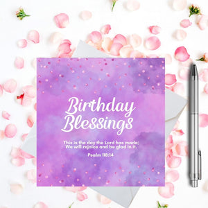 Pink and purple "Birthday Blessings" Card. Surrounded by a pretty pink confetti. The card is on a white envelope with silver pen. - White text says "Birthday Blessings" and the words of Psalm 118:14. A pink petal background.