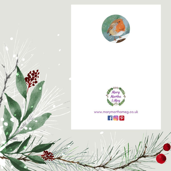 The back of a Mary, Martha & Meg Christmas Greetings card shows a smaller, circular image of the winter robin, which features on the front of the card. The Mary, Martha & Meg logo is also featured, with a reference to this Christian business website: www.marymarthameg.co.uk as well as the logos for Facebook, Instagram and Pinterest, where this Mary, Martha & Meg can be contacted. The white card is photographed on a background of seasonal leaves and red berries.