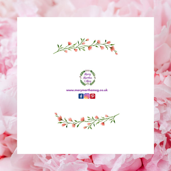 The reverse of a floral wreath greeting card by Mary, Martha & Meg, pictured against a background of pink rose petals. The card shows the Mary, Martha & Meg logo at its centre, underneath are references to Mary, Martha & Meg social media sites. Above and below the images are a delicate spray of pink flowers and green leaves. 